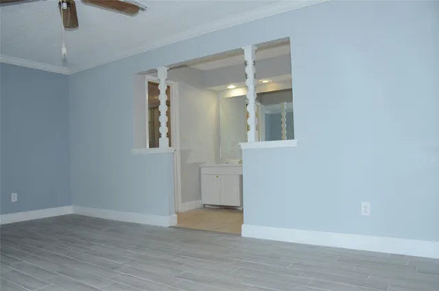 an empty room with wooden floor cabinet and windows