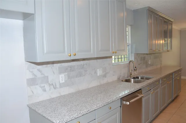 a kitchen with stainless steel appliances granite countertop a sink and a white cabinets