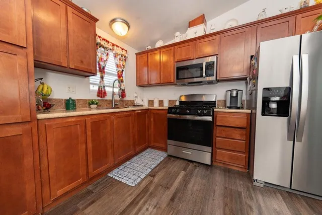 a kitchen with stainless steel appliances granite countertop a refrigerator stove a sink and dishwasher with wooden floor