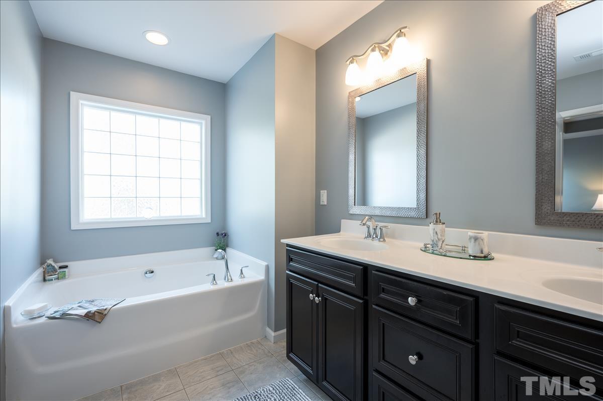4625 Pat Reed Road Raleigh, NC 27616 - Photo 18 of 28 a bathroom with a tub a sink double vanity and a mirror