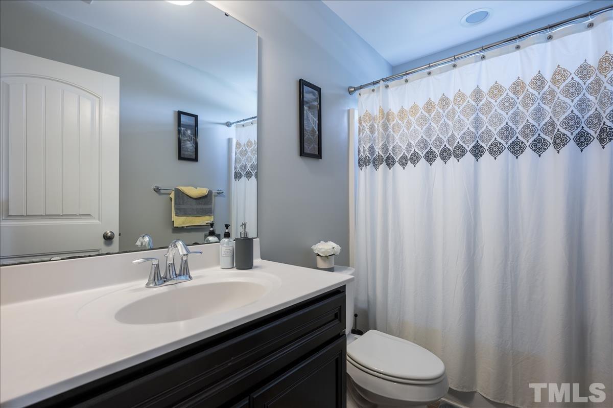 4625 Pat Reed Road Raleigh, NC 27616 - Photo 20 of 28 a bathroom with a sink a toilet a shower curtain and a large mirror
