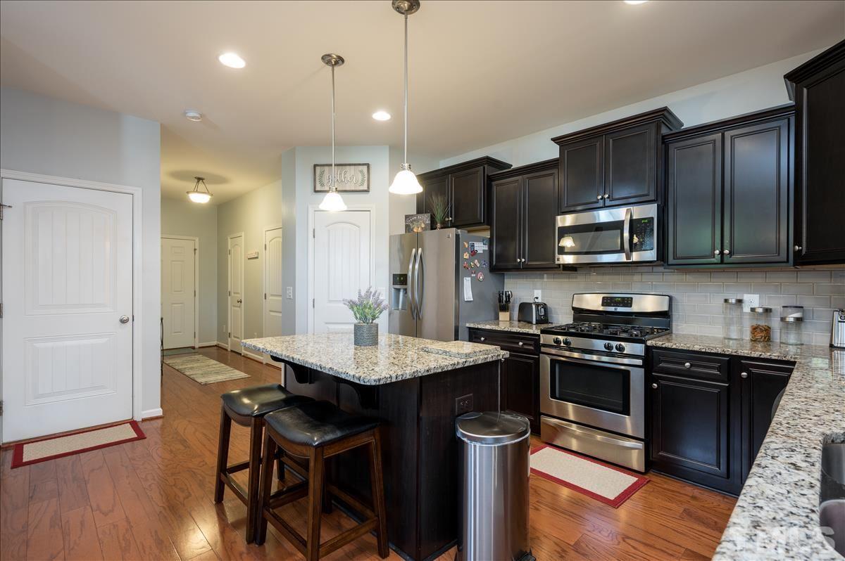 4625 Pat Reed Road Raleigh, NC 27616 - Photo 5 of 28 a kitchen with stainless steel appliances granite countertop a table chairs sink refrigerator and cabinets