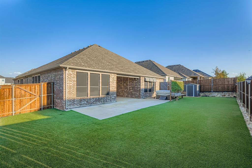312 Magnolia Drive Oak Point, TX 75068 - Photo 27 of 28 Back of property featuring a shingled roof, brick siding, a fenced backyard, a patio, and a gate