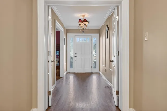 a view of a hallway with wooden floor and chandelier