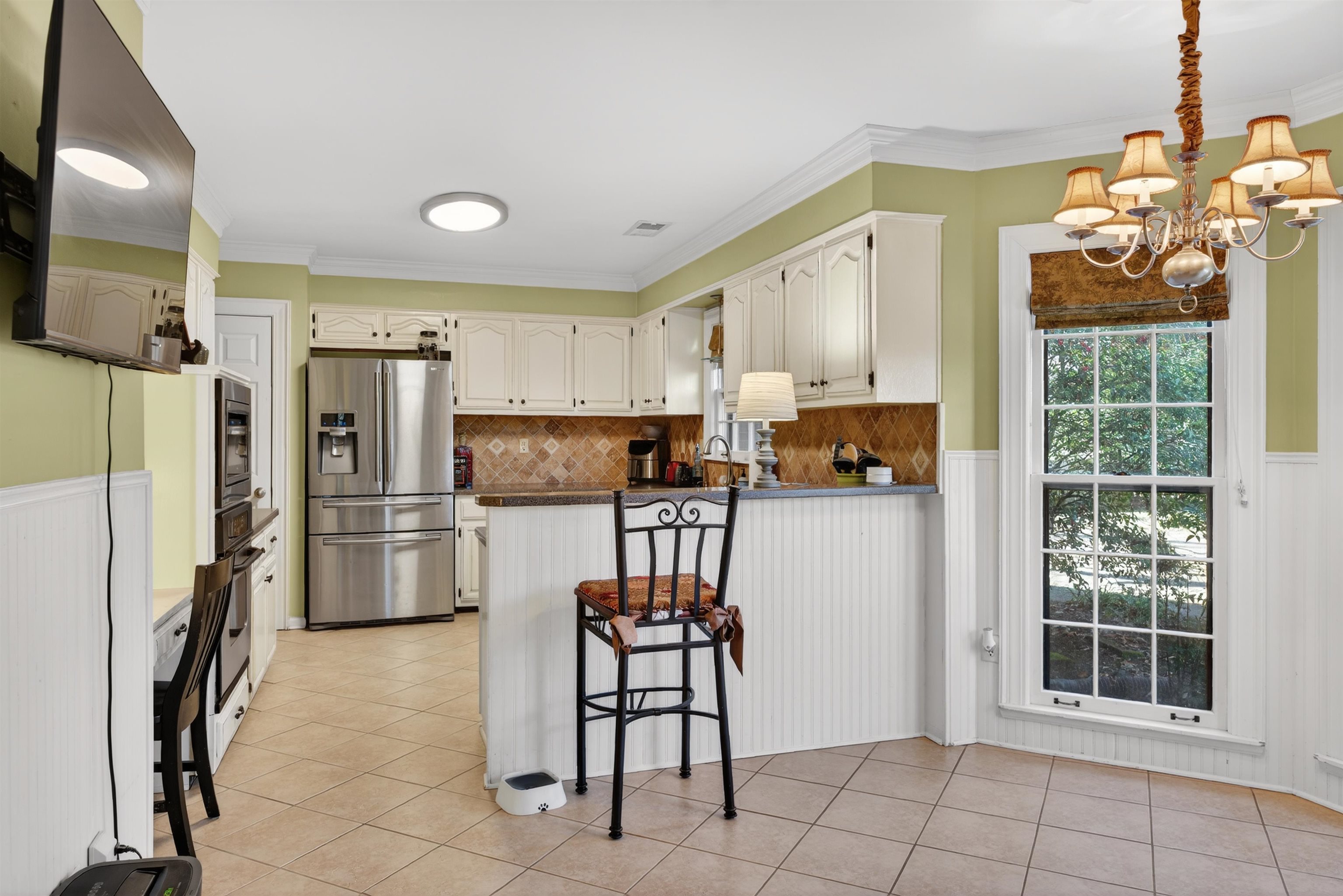 1195 Frank Road Collierville, TN 38017 - Photo 23 of 35 Kitchen with a wainscoted wall, a peninsula, appliances with stainless steel finishes, ornamental molding, and hanging light fixtures