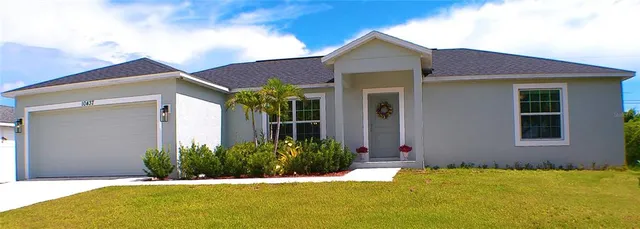 a view of a house with palm plants and a yard