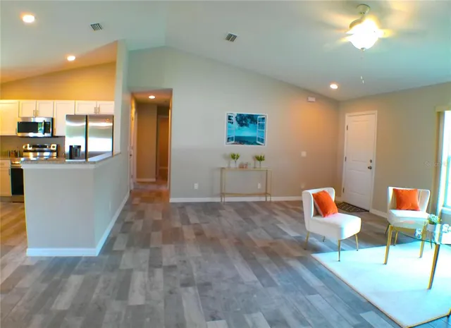 a living room with furniture a rug and kitchen view