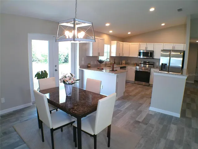 a kitchen with a dining table chairs stainless steel appliances and cabinets