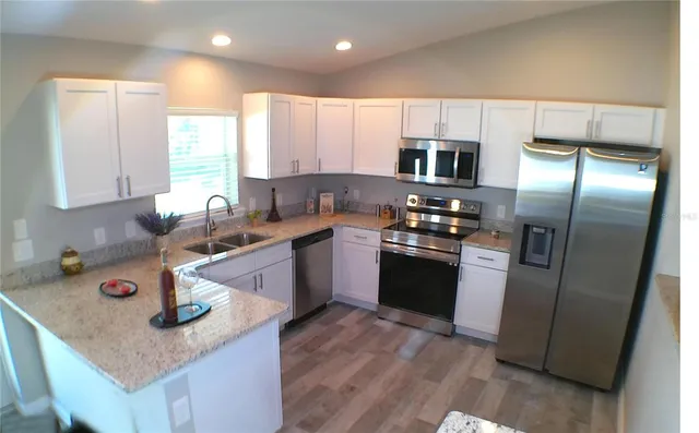 a kitchen with granite countertop a sink a counter space stainless steel appliances and cabinets