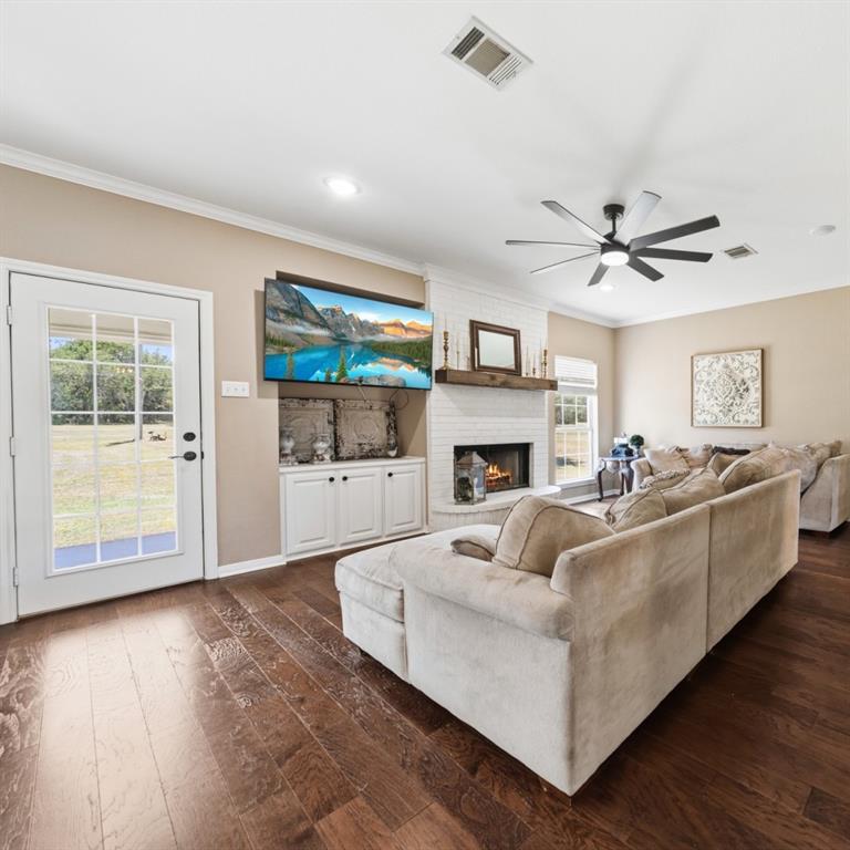 785 Tweedy Road Valley Mills, TX 76689 - Photo 8 of 40 Living area featuring wood-finish flooring, a white painted brick fireplace with a wood mantel, recessed lighting, and a multi-blade ceiling fan