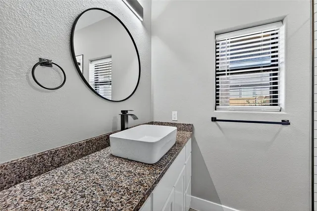 a bathroom with a granite countertop sink and a mirror