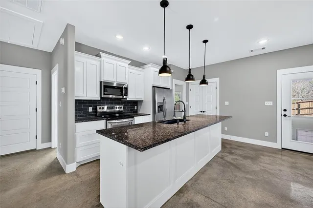a kitchen with stainless steel appliances granite countertop a sink a microwave a refrigerator and white cabinets