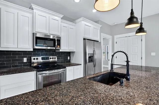 a kitchen with granite countertop a stove a sink and a microwave