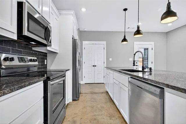 a kitchen with stainless steel appliances granite countertop a stove a sink and a microwave