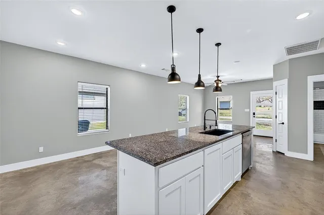 a kitchen with granite countertop a sink a center island and stainless steel appliances
