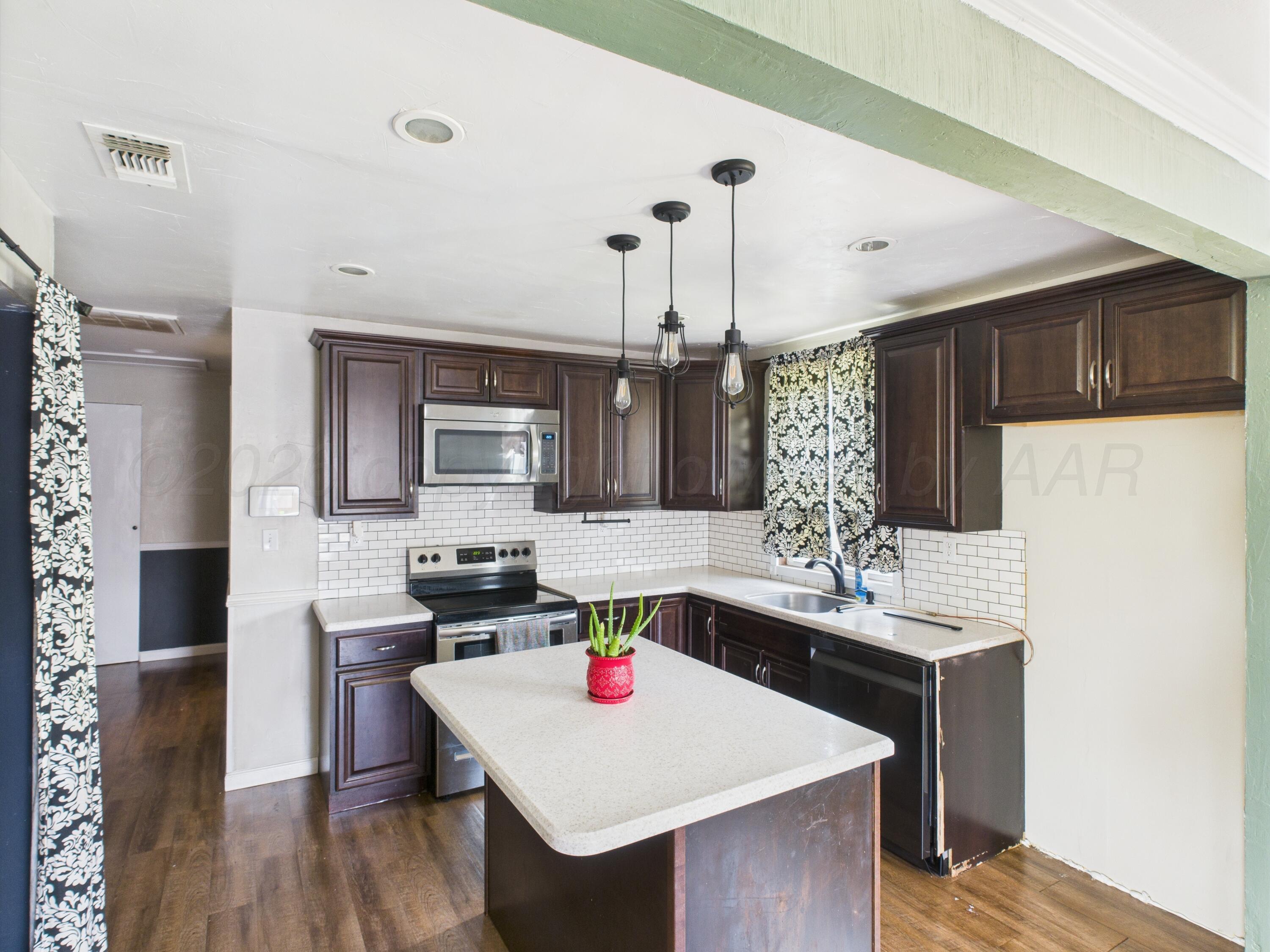 505 South Ridgeland Avenue Fritch, TX 79036 - Photo 2 of 19 a kitchen with a stove a refrigerator and a dining table with wooden floor
