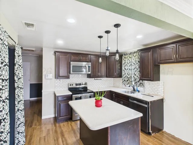a kitchen with a stove a refrigerator and a dining table with wooden floor