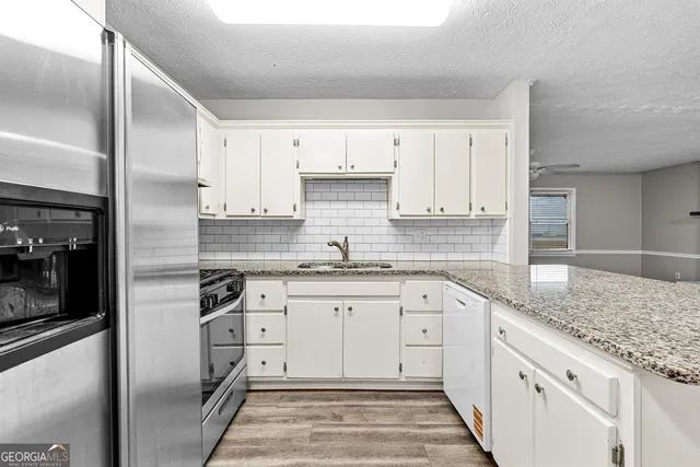 a kitchen with granite countertop white cabinets and stainless steel appliances