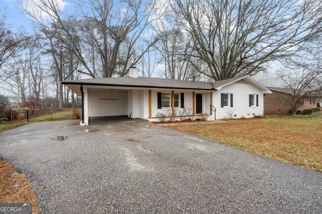 a view of house with yard and trees in the background