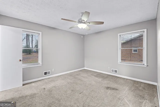 an empty room with a window and ceiling fan
