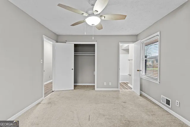 an empty room with closet and a ceiling fan