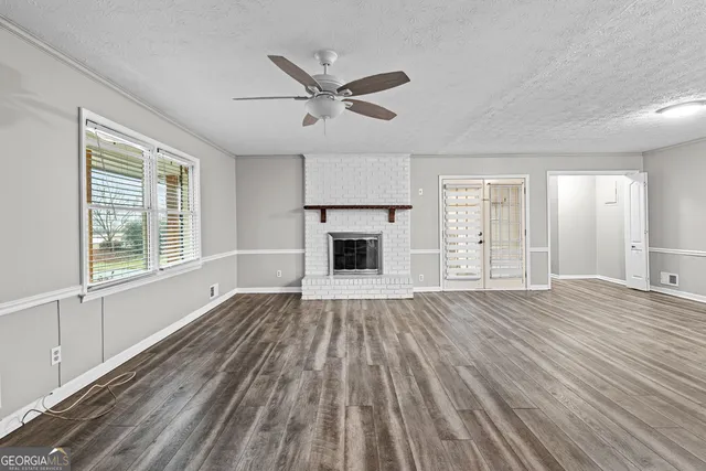 an empty room with wooden floor fireplace and windows