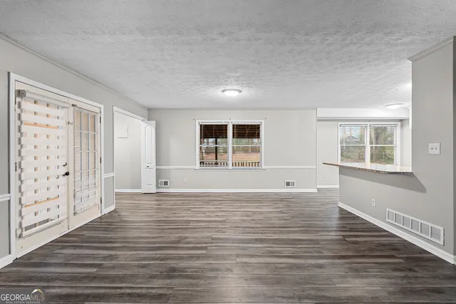 a view of an empty room with a window and wooden floor