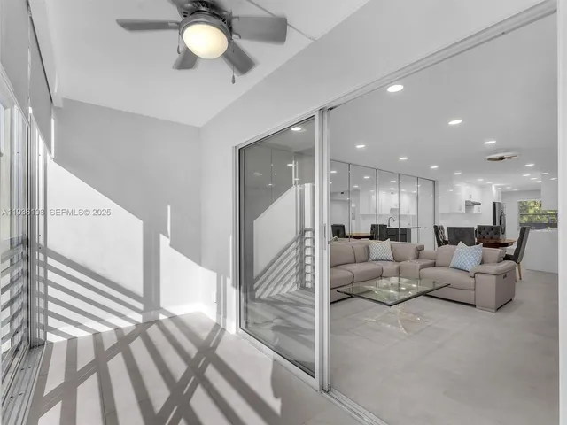 a living room with couches and kitchen view with wooden floor