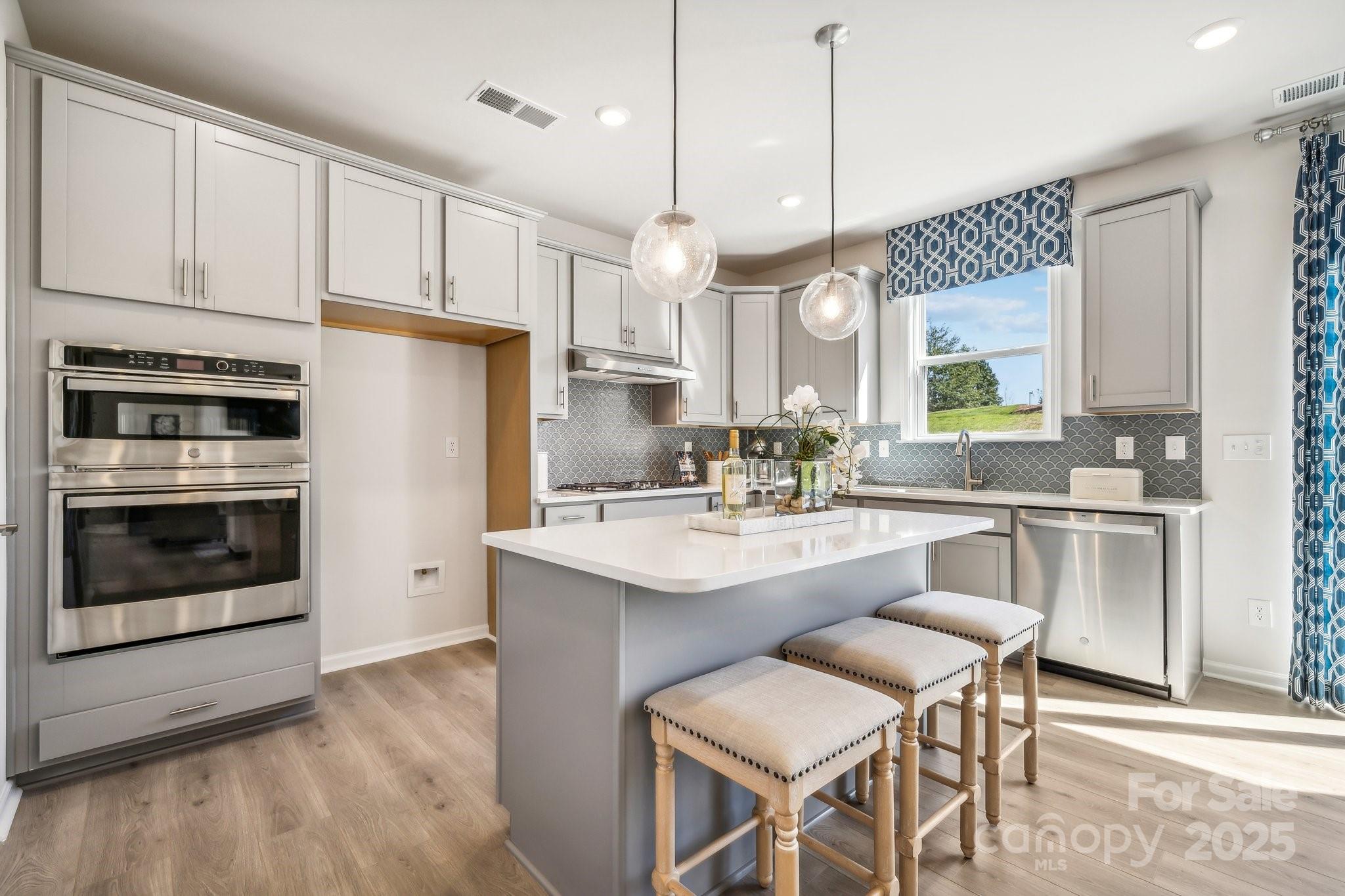 1476 Hubert Graham Way Tega Cay, SC 29708 - Photo 11 of 31 a kitchen with white cabinets and stainless steel appliances