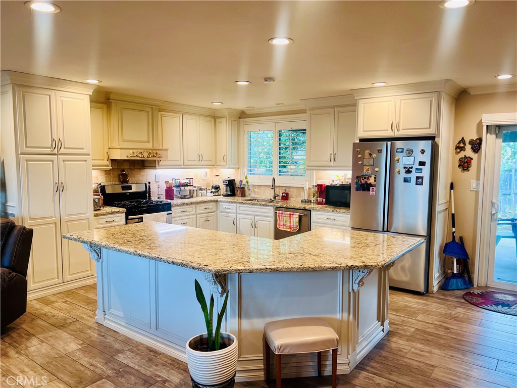 a kitchen with stainless steel appliances granite countertop a refrigerator a sink and a stove