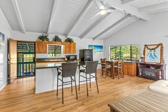 a living room with stainless steel appliances granite countertop furniture wooden floor and a large window