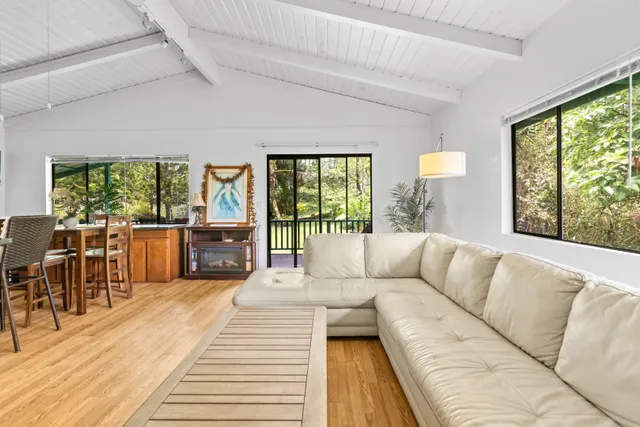 a living room with furniture large windows and wooden floor