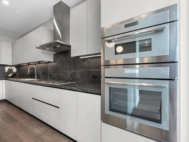 a kitchen with granite countertop white cabinets and white stainless steel appliances