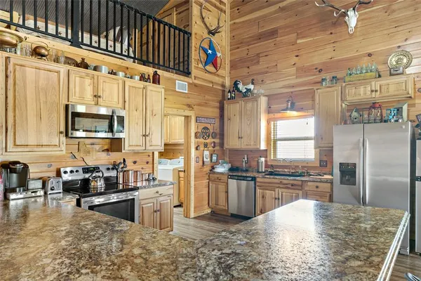 a kitchen with stainless steel appliances granite countertop a refrigerator a stove and a sink with cabinets