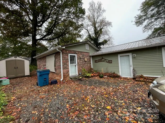 a backyard of a house with wooden fence and a large tree