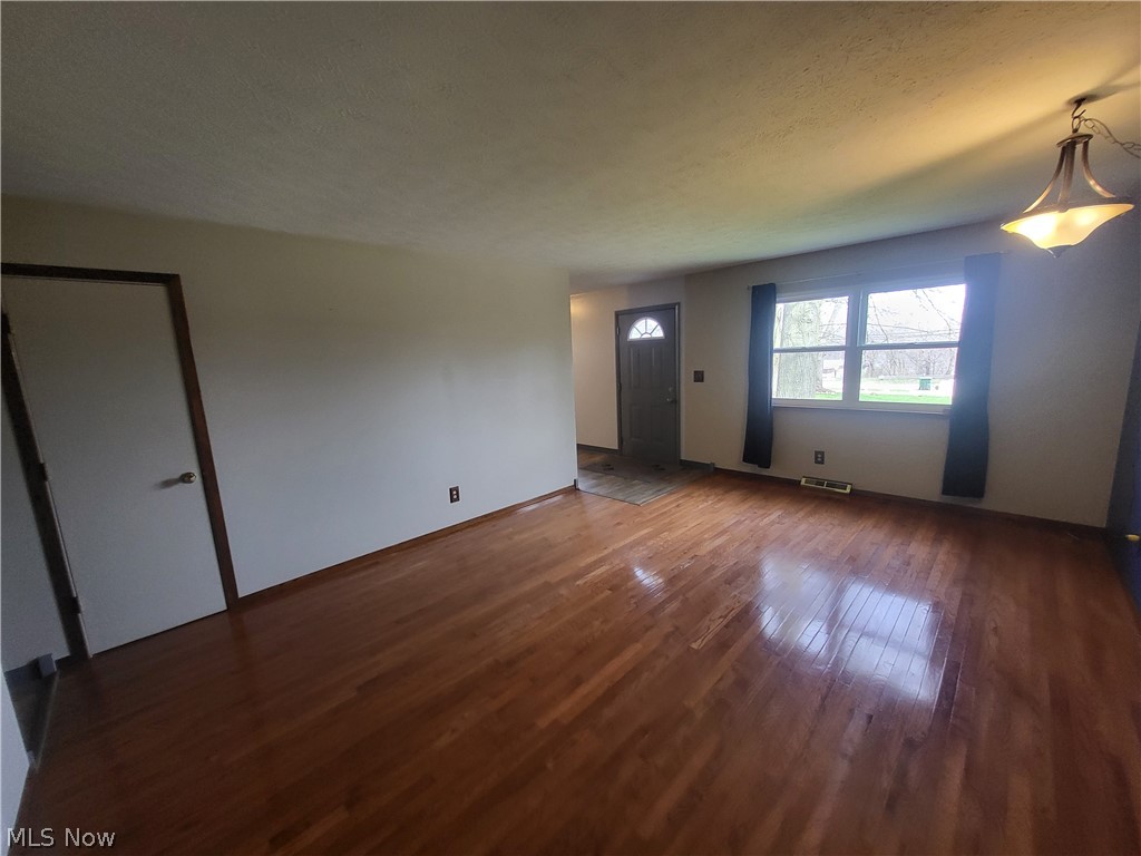 Empty room featuring dark hardwood / wood-style flooring