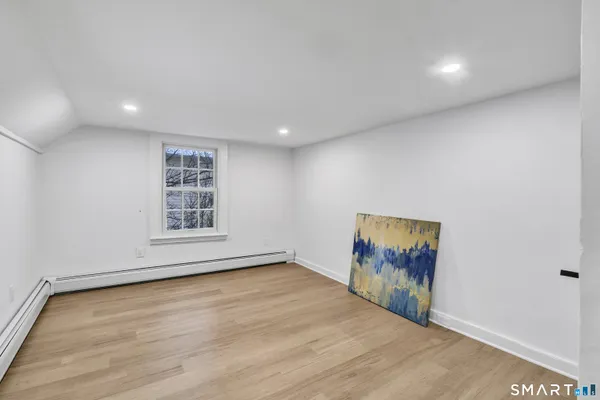 a view of an empty room with a window and wooden floor