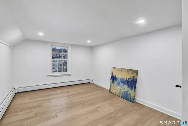 a view of an empty room with a window and wooden floor