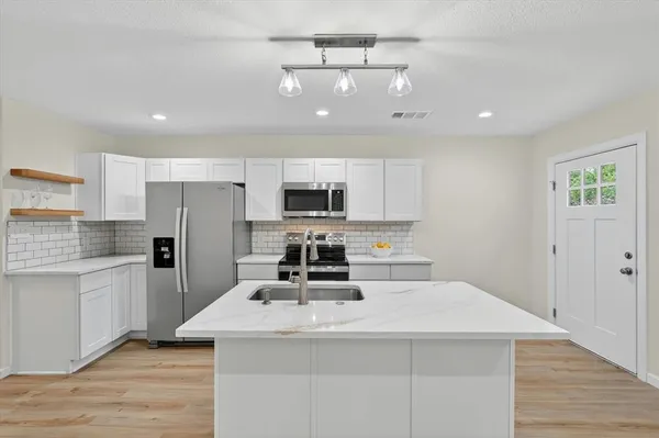 a kitchen with kitchen island a white counter top space cabinets and stainless steel appliances