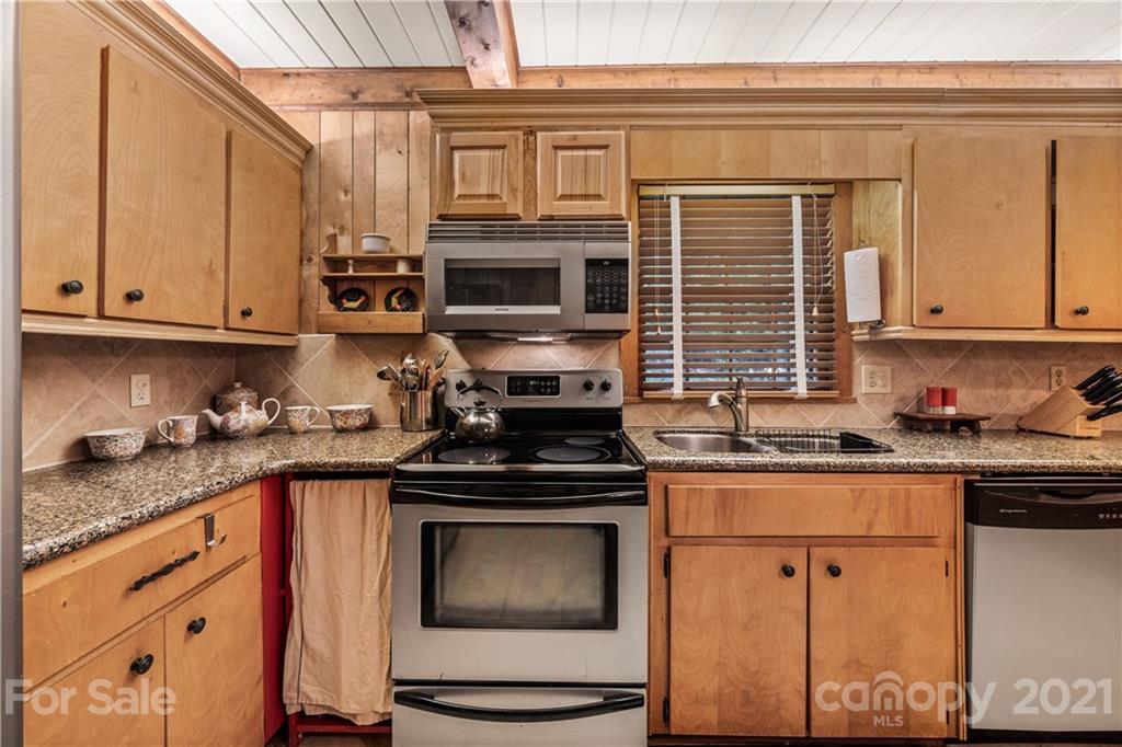 602 Quail Cove Road Clyde, NC 28721 - Photo 29 of 48 a kitchen with stainless steel appliances granite countertop a stove top oven a sink dishwasher and cabinets with wooden floor