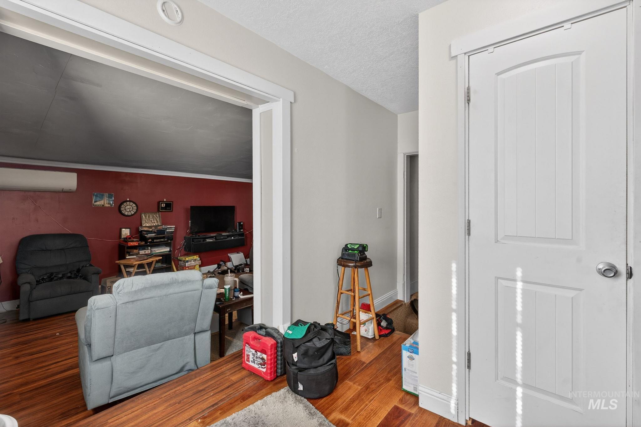 208 South 4th W Street Preston, ID 83263 - Photo 12 of 38 Living room with wood finished floors, a textured ceiling, and a wall mounted air conditioner