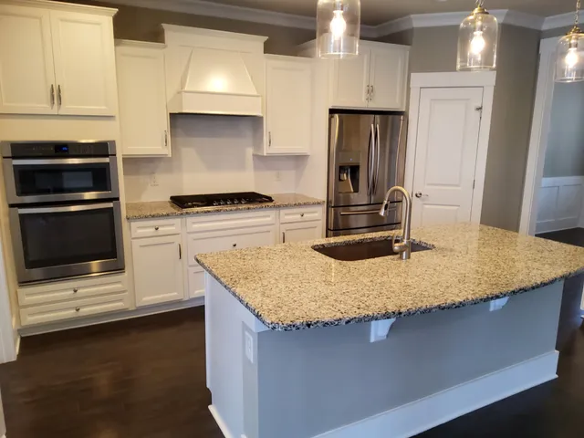 a kitchen with kitchen island granite countertop a stove and a sink