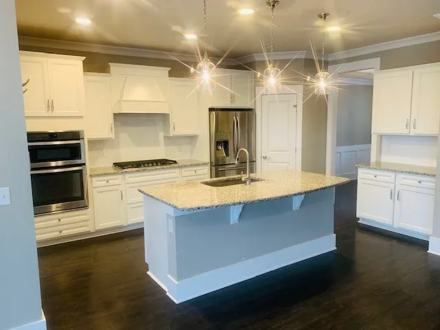 a kitchen with stainless steel appliances granite countertop a sink a stove and a refrigerator