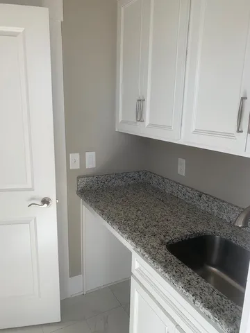 a kitchen with granite countertop white cabinets and a sink