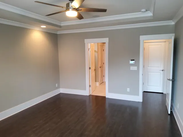 an empty room with wooden floor and a ceiling fan