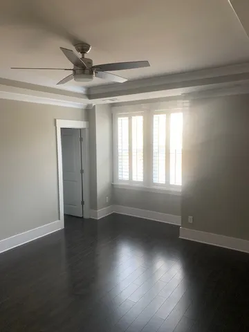 an empty room with wooden floor fan and windows