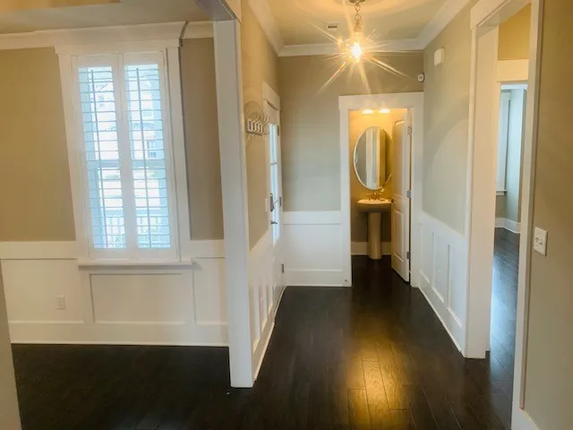 a view of a hallway with wooden floor and a bathroom