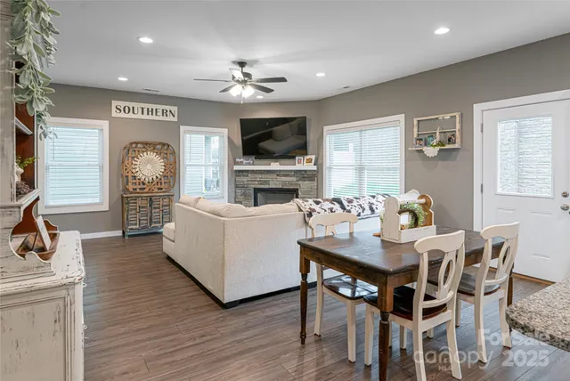 a kitchen with stainless steel appliances granite countertop a refrigerator a stove top oven a sink dishwasher a dining table and chairs with wooden floor