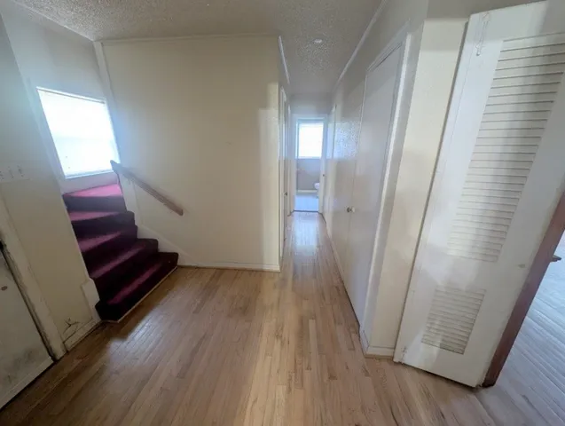 a view of a hallway with wooden floor and stairs