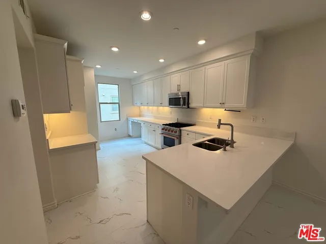 a kitchen with stainless steel appliances a sink a stove a refrigerator and cabinets